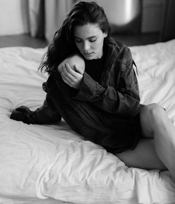 Woman in a calm, gentle stretching pose in a dark room.